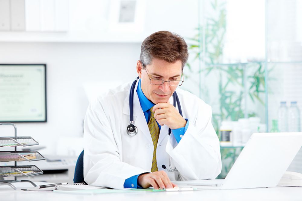 Foto: Arzt sitzt vor Laptop