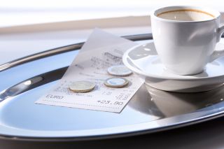Foto: Trinkgeld auf Tablett mit leerer Kaffeetasse