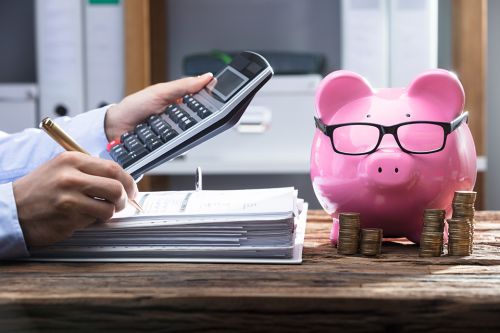 Foto: Hände mit Aktenordner, Taschenrechner und Sparschwein