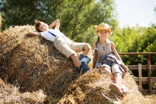 Foto: Zwei Kinder sitzen auf Heuhaufen