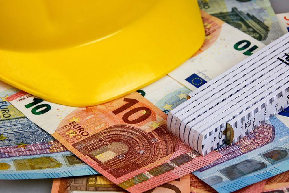 Foto: Bauhelm, Zollstock und Geldscheine